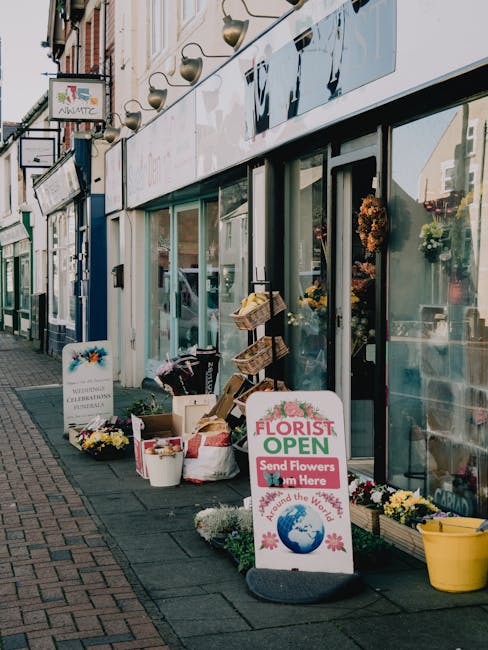 Outdoor display of a florist shop on Stanmore High Street showcasing a variety of fresh flower arrangements in buckets and baskets, with colorful blooms including chrysanthemums and daisies, arranged 